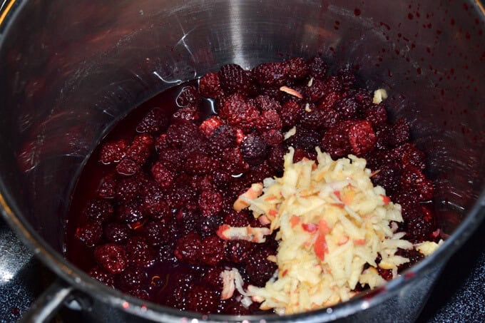grated apples and blackberries in a stockpot to make black berry jam