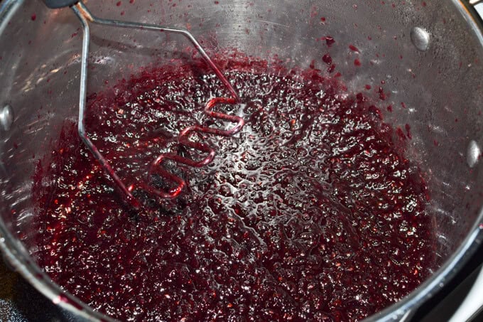 grated apples and blackberries all mashed up in a stockpot to make black berry jam