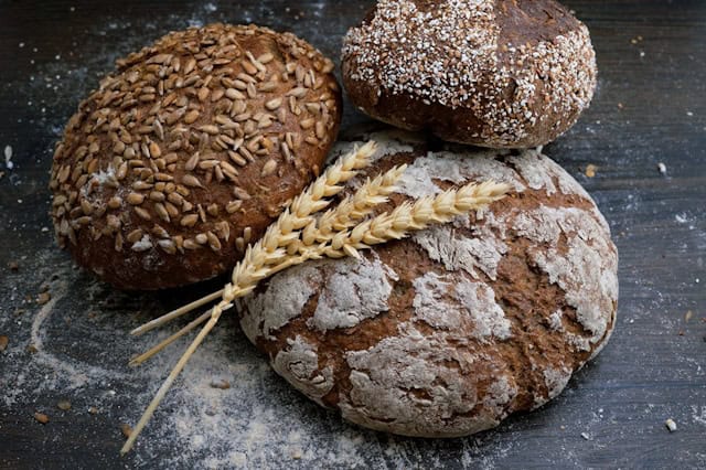 Three loaves of bread on a black wooden table.