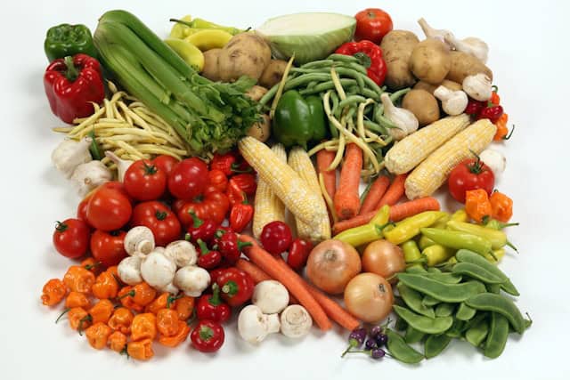 A variety of different vegetables lying on a white table.