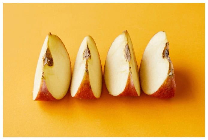 four slices of apples side by side on a yellow background