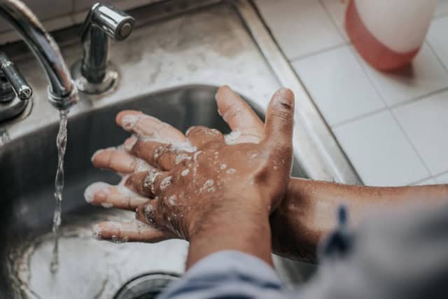 Someone washing their hands with soap at a kitchen sink.