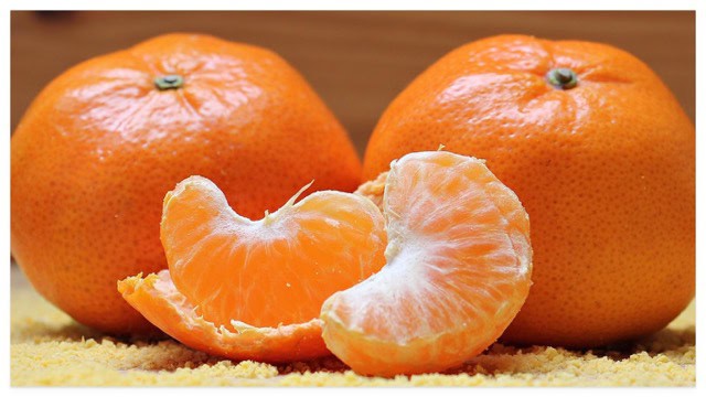 Two clementines next to two slices and a peel.