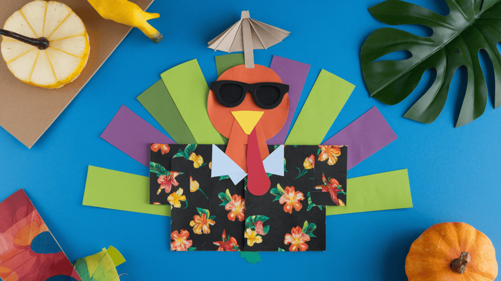 A flat tourist turkey disguise idea. It has a Hawaiian shirt pattern, basic sunglasses made from black paper, and a tiny paper umbrella on top